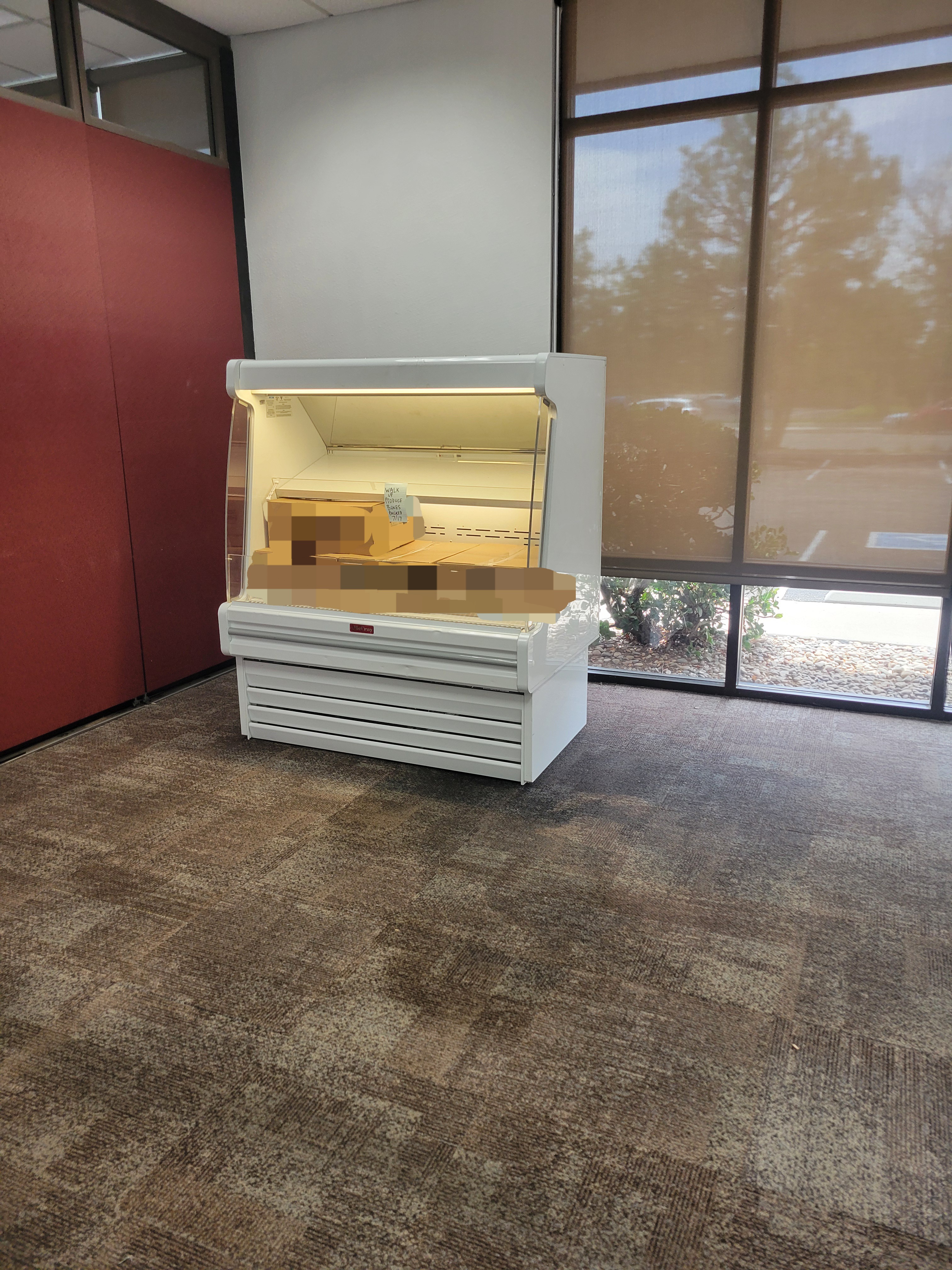 Refrigerated display case filled with boxes for after hours walk up clients.